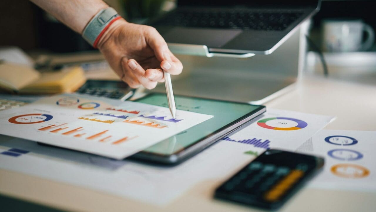 Person pointing to graphs and charts on a desk