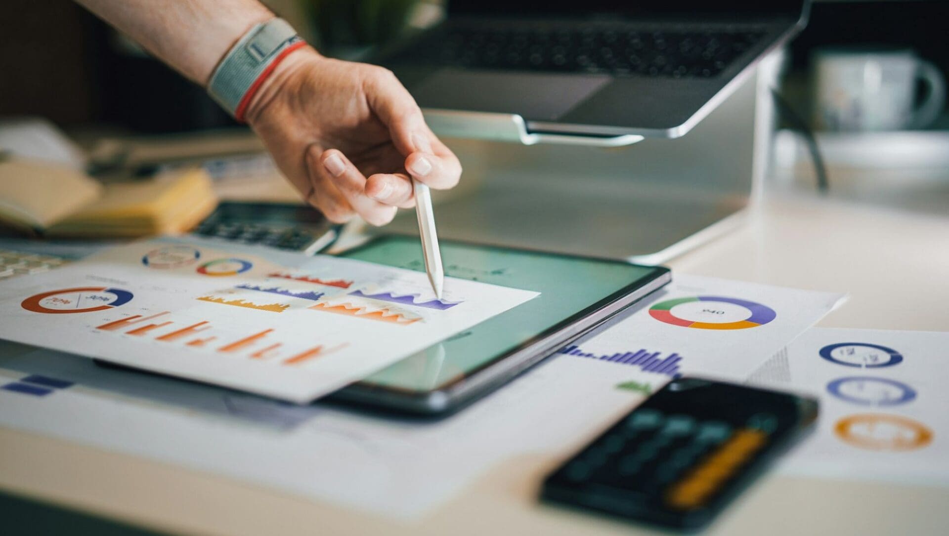 Person pointing to graphs and charts on a desk